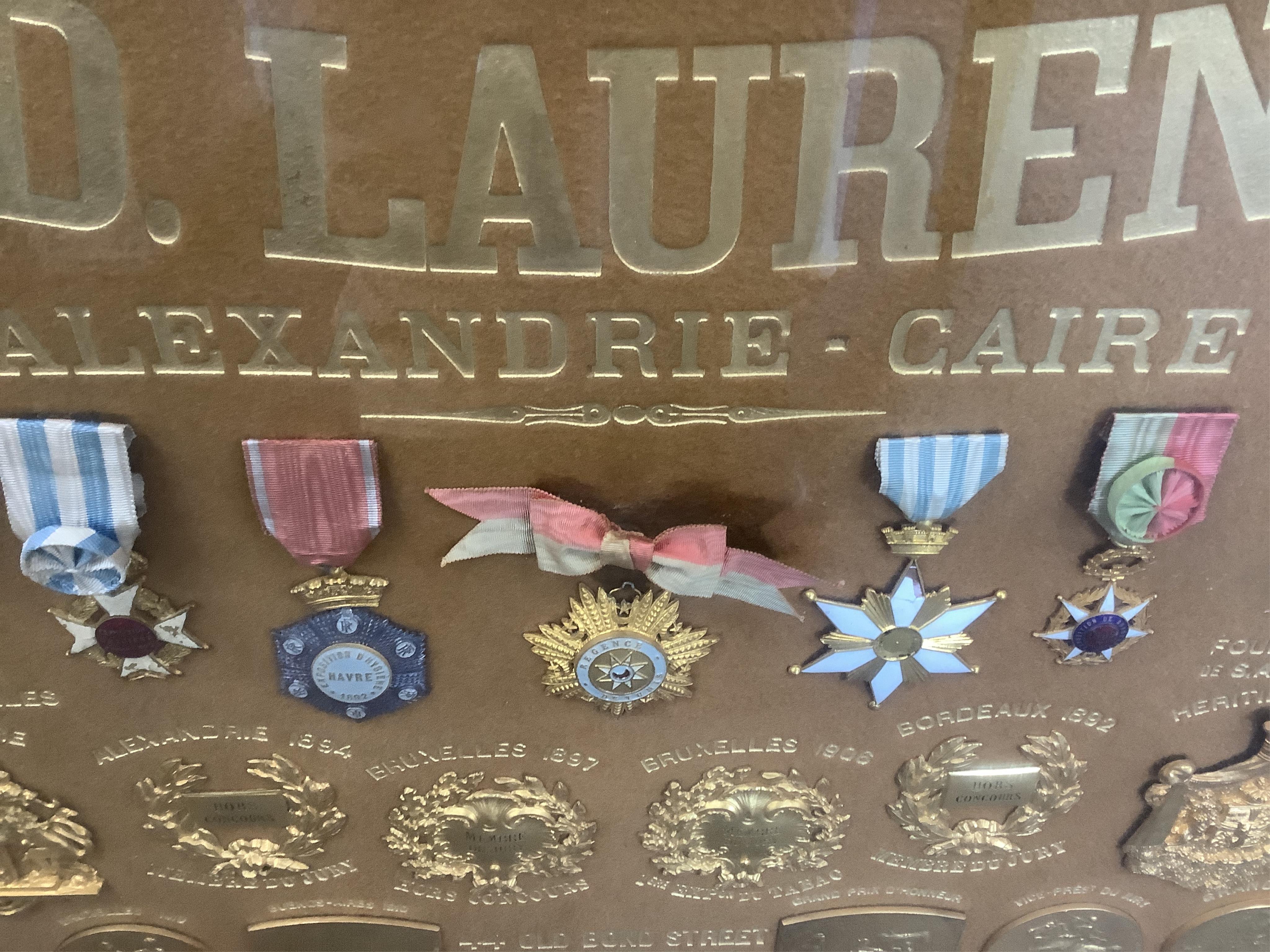 Smoking interest, a large oak framed display of gilt and enamel metal medals to Ed. Laurens, early 20th century, Containing gilt bronze prize medals, ranging from 1890-1906, various gilt and enamel medals with ribbons an
